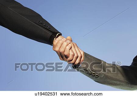 Businesspeople shaking hands against clear sky View Large Photo Image Stock Image - Businesspeople shaking hands against clear sky. Fotosearch