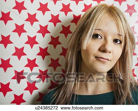 Close-up of beautiful young woman against red star shapes wallpaper View Large Photo Image Stock Image - Close-up of beautiful young woman against red star shapes wallpaper. Fotosearch