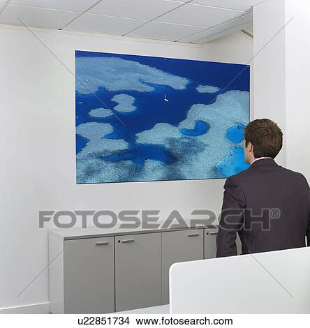 Contemplative mid-adult businessman looking at painting on wall in office View Large Photo Image Picture - Contemplative mid-adult businessman looking at painting on wall in office. Fotosearch