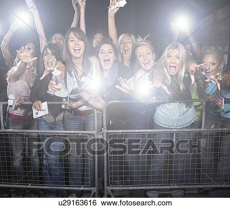 Stock Photograph - Crowd of young female fans screaming and cheering at concert. Fotosearch