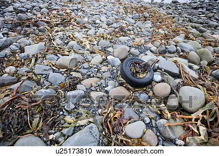 Stock Image - Discarded tire litters a beach, Ireland. Fotosearch