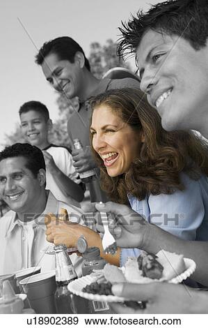 Stock Photo - Family and friends enjoying at barbecue. Fotosearch
