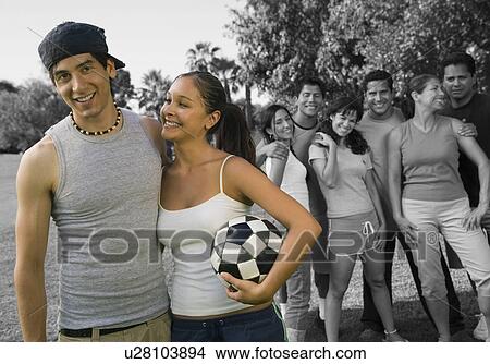 Happy couple holding soccer ball enjoying with friends at park View Large Photo Image Picture - Happy couple holding soccer ball enjoying with friends at park. Fotosearch