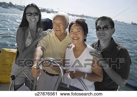 Stock Image - Happy Japanese family sailing together on yacht. Fotosearch