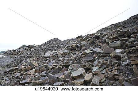 Stock Image - Looking past several piles of different rocks in a quarry. Fotosearch