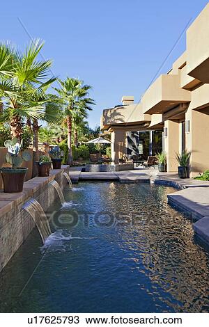 Stock Image - Luxury Villa with waterfall feature and palm trees. Fotosearch