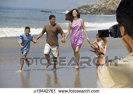 Man video recording happy Hispanic Latin family walking at beach View Large Photo Image Stock Image - Man video recording happy Hispanic Latin family walking at beach. Fotosearch