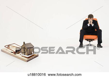 Model home on mouse trap with worried businessman sitting on chair representing increasing real estate rates View Large Photo Image Stock Photograph - Model home on mouse trap with worried businessman sitting on chair representing increasing real estate rates. Fotosearch