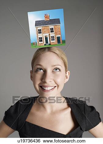Model home on top of young woman's head representing homeownership View Large Photo Image Stock Photograph - Model home on top of young woman's head representing homeownership. Fotosearch