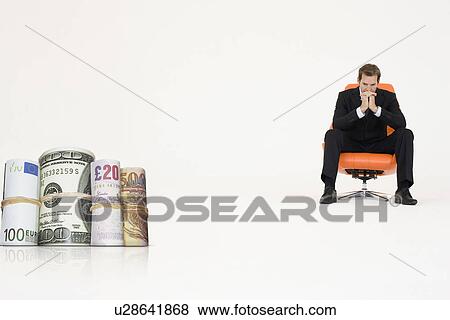 Money rolls with pensive businessman on chair representing financial problems View Large Photo Image Stock Photo - Money rolls with pensive businessman on chair representing financial problems. Fotosearch