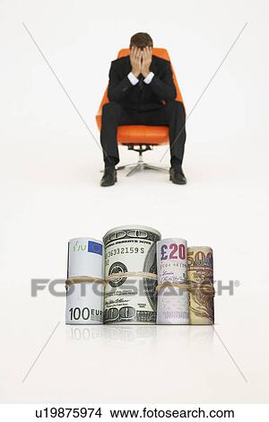 Money rolls with worried businessman on chair representing financial problems View Large Photo Image Picture - Money rolls with worried businessman on chair representing financial problems. Fotosearch