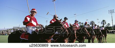 Stock Photo - Panoramic shot of polo players and umpire on horses at field. Fotosearch