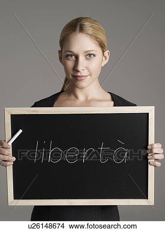 Picture - Portrait of young businesswoman holding blackboard with Italian text "libertà" (Freedom). Fotosearch