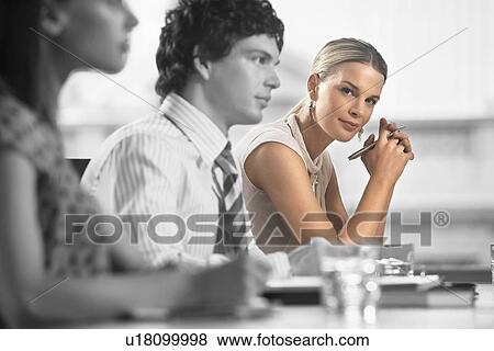 Stock Photo - Portrait of young businesswoman with colleagues in a meeting. Fotosearch