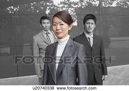 Stock Photo - Portrait of young businesswoman with coworkers outside office building. Fotosearch