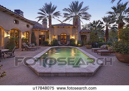 Stock Photography - Rear entrance of luxury villa at night with swimming pool. Fotosearch