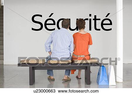 Stock Image - Rear view of couple reading French text "sécurité" (security) and contemplating about security. Fotosearch