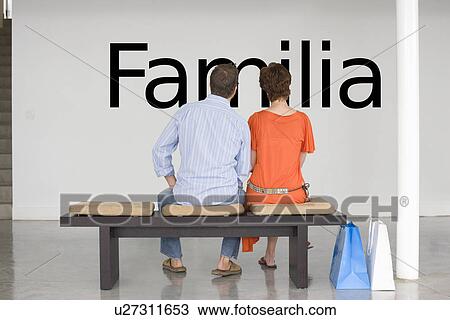Rear view of couple seated on bench reading Spanish text "Familia" (family) on wall View Large Photo Image Stock Image - Rear view of couple seated on bench reading Spanish text "Familia" (family) on wall. Fotosearch