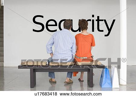 Rear view of couple seated on bench contemplating about future security View Large Photo Image Stock Photo - Rear view of couple seated on bench contemplating about future security. Fotosearch