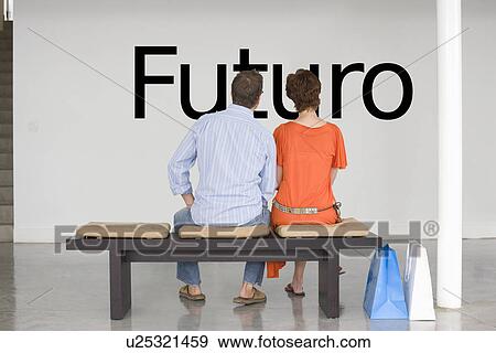 Rear view of couple seated on bench reading Spanish text "Futuro" (future) on wall View Large Photo Image Stock Photo - Rear view of couple seated on bench reading Spanish text "Futuro" (future) on wall. Fotosearch