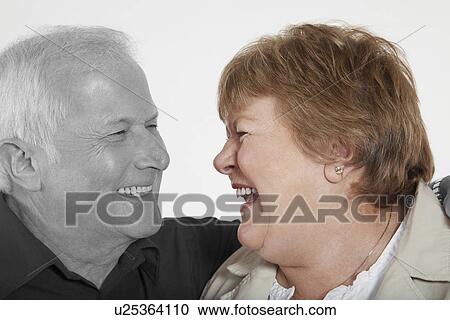 Stock Image - Senior couple looking at each other against white background. Fotosearch