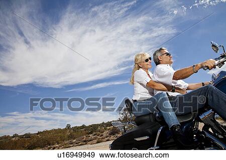 Stock Photo - Senior couple riding motorcycle on desert road. Fotosearch