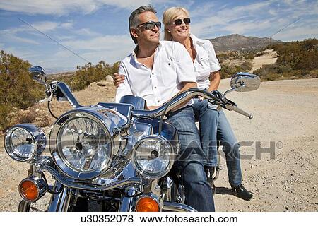 Senior couple wear sunglasses seated on motorcycle on desert road View Large Photo Image Stock Photo - Senior couple wear sunglasses seated on motorcycle on desert road. Fotosearch