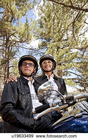 Senior couple wearing helmets stand next to motorcycle View Large Photo Image Stock Photo - Senior couple wearing helmets stand next to motorcycle. Fotosearch