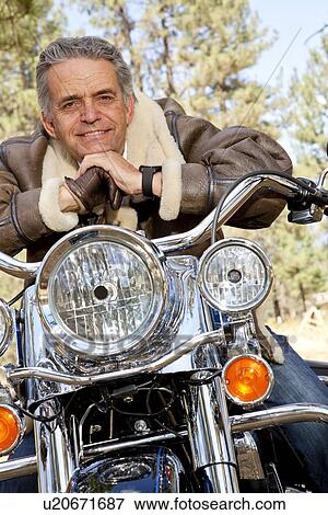 Stock Photo - Senior man leaning on motorcycle handlebars. Fotosearch