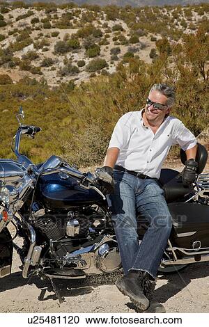 Senior man leans on motorcycle in desert View Large Photo Image Stock Image - Senior man leans on motorcycle in desert. Fotosearch