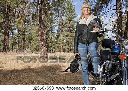Senior woman poses with motorcycle in forest View Large Photo Image Stock Image - Senior woman poses with motorcycle in forest. Fotosearch