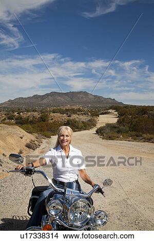 Senior woman riding motorcycle on desert road View Large Photo Image Picture - Senior woman riding motorcycle on desert road. Fotosearch
