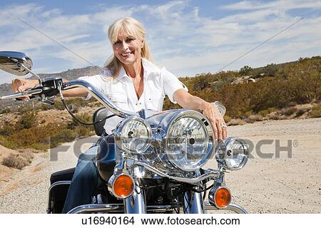 Senior woman sits on motorcycle on desert road View Large Photo Image Picture - Senior woman sits on motorcycle on desert road. Fotosearch