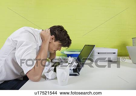 Side view of frustrated young businessman with paper balls and laptop on desk View Large Photo Image Picture - Side view of frustrated young businessman with paper balls and laptop on desk. Fotosearch