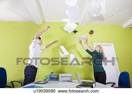 Side view of young businesspeople throwing documents in office View Large Photo Image Stock Image - Side view of young businesspeople throwing documents in office. Fotosearch