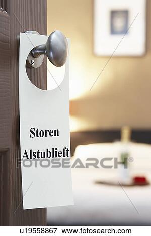Stock Photo - Sign with Dutch text "Storen Alstublieft" (please disturb) hanging on hotel room door. Fotosearch