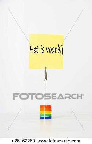 Stock Image - Sticky notepaper with Dutch text "Het is voorbij" (It's over) clipped to a multicolored card holder. Fotosearch