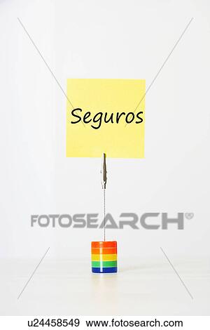 Stock Photo - Sticky notepaper with Spanish text "seguros" (Insurance) clipped to a multicolored card holder. Fotosearch