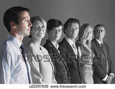 Stock Photo - Team of professionals looking at colleague against gray background. Fotosearch