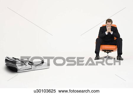 Stock Photography - Wad of cash on mouse trap with pensive businessman on chair representing financial difficulties. Fotosearch