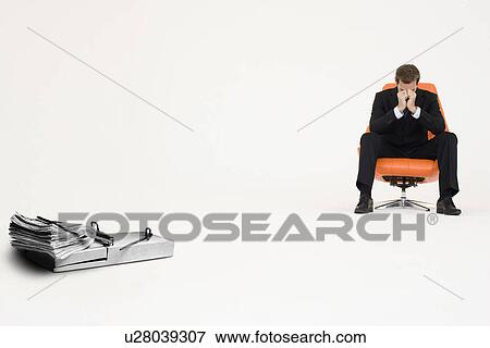 Stock Photo - Wad of cash on mouse trap with worried businessman sitting on chair representing financial difficulties. Fotosearch