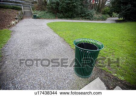 Picture - Wide angle view of trash can by a path in a park. Fotosearch