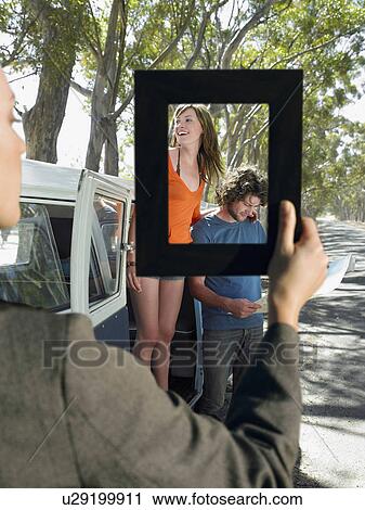 Woman framing a young couple standing by van on a road trip View Large Photo Image Stock Image - Woman framing a young couple standing by van on a road trip. Fotosearch