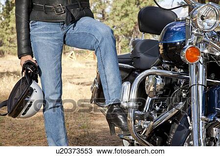 Stock Image - Womans leg rests on motorcycle foot rest. Fotosearch
