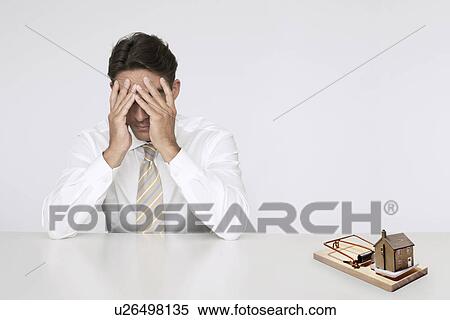 Worried businessman at table model home in mouse trap representing expensive real estate costs View Large Photo Image Stock Photography - Worried businessman at table model home in mouse trap representing expensive real estate costs. Fotosearch