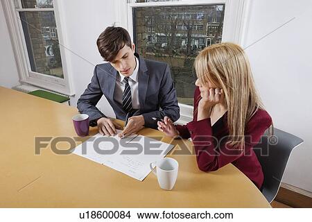 Picture - Young businessman and female colleague with paperwork at conference table. Fotosearch