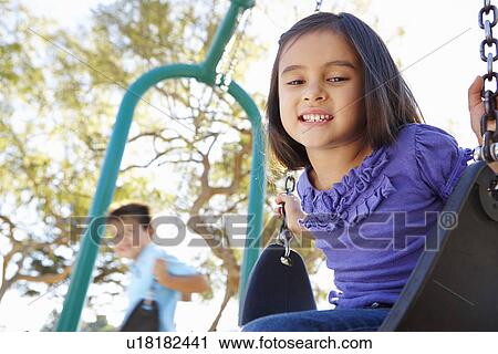Stock Image - Boy And Girl Playing On Swing In Park. Fotosearch