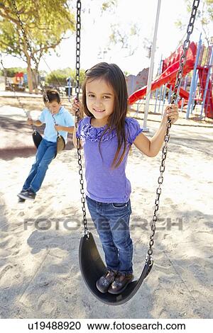 Stock Image - Boy And Girl Playing On Swing In Park. Fotosearch