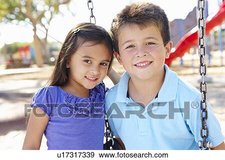 Boy And Girl Playing On Swing In Park View Large Photo Image Stock Photo - Boy And Girl Playing On Swing In Park. Fotosearch