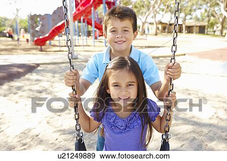 Boy And Girl Playing On Swing In Park View Large Photo Image Stock Photo - Boy And Girl Playing On Swing In Park. Fotosearch
